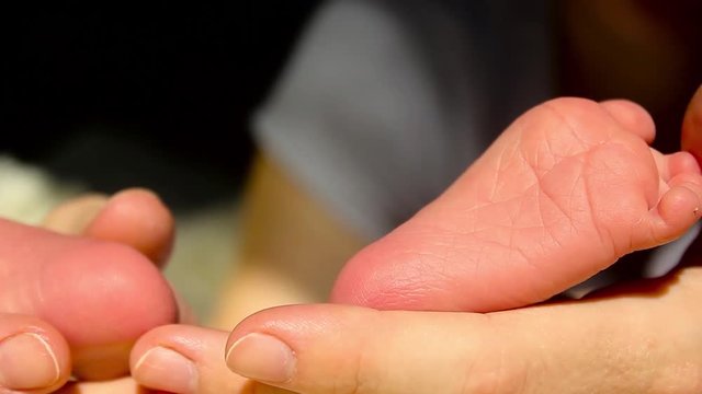 Baby feet in mother hands. Tiny Newborn Baby's feet on female Heart Shaped hands closeup. Mom and her Child. Happy Family concept. Beautiful conceptual video of Maternity.