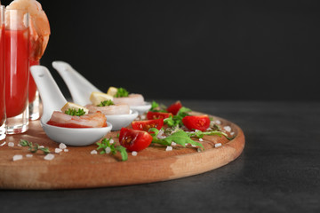 Board with spoons of tomato sauce and shrimps on table, closeup