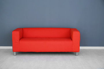 Comfortable red sofa near color wall