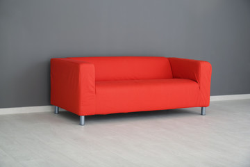 Comfortable red sofa near color wall