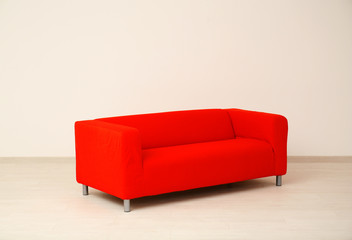 Comfortable red sofa near light wall