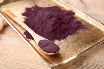 Metal tray with acai powder and spoon on wooden background