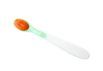Plastic spoon with baby food on white background