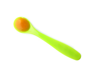 Plastic spoon with baby food on white background