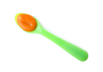Plastic spoon with baby food on white background