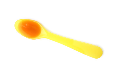 Plastic spoon with baby food on white background