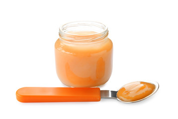Spoon and jar with baby food on white background