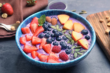 Healthy breakfast with delicious acai smoothie in bowl on table