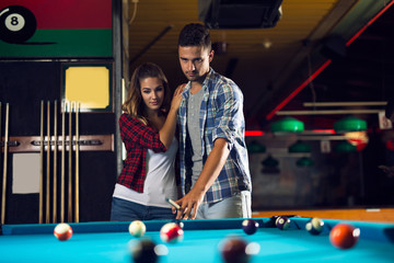 Couple dating and playing billiard in a pool hall