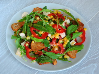 Salad on a plate. Fitness salad with corn. Nutritious fitness salad.Arugula corn pepper cheese. Top view.