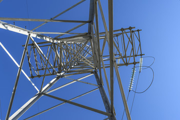 Supports high-voltage power lines against the blue sky. View fro