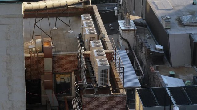 Daytime high angle view of running air conditioner units atop buildings in Manhattan.  	