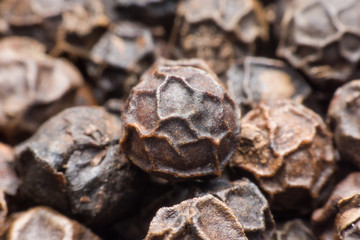 Black pepper grains as background close up