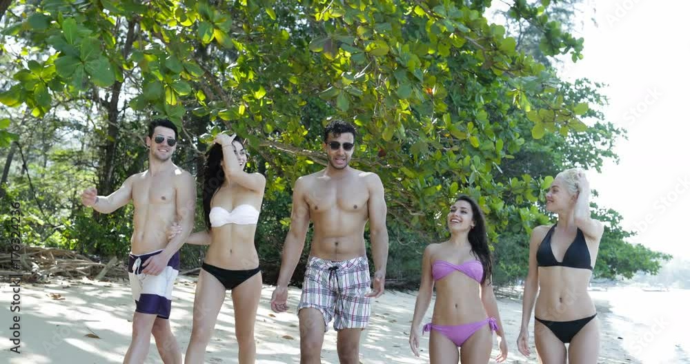 Wall mural people in swimwear walking on beach talking, young man and woman group communication tropical vacati