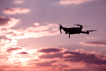 Silhouette of drone hovering in a colorful sunset. Toned image. Soft focus