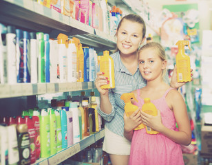 mother with daughter holding spray  of sun protection
