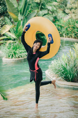 excited young woman with inflatable tube in a pool