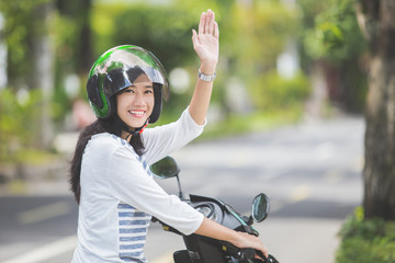 woman riding a motorbike and waving hand