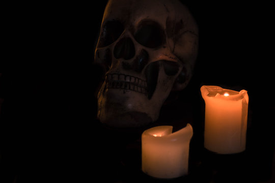Skull in the dark lightened by candles
