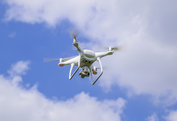 Flight quadrocopters white against the blue sky with clouds