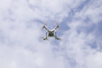 Flight quadrocopters white against the blue sky with clouds