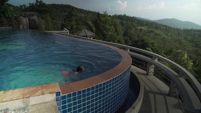 Young girl is swimming in pool atop a mountain stock footage video