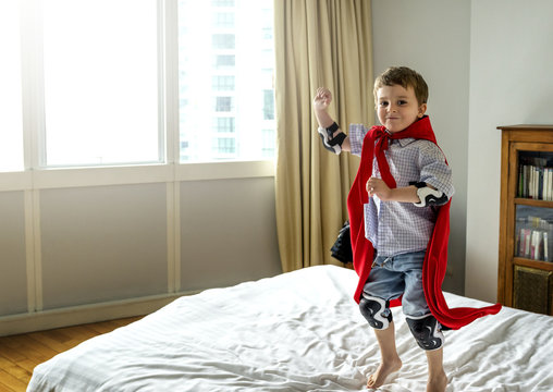 Boy playing superhero in bed