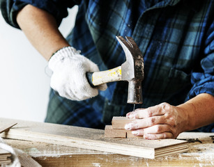 Woman carpenter using hammer pushing nail on a wood