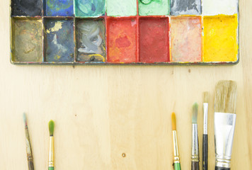 Artist paint brushes and palette on wooden background
