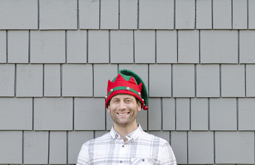 Man smiling ready for the Christmas season with a red and green hat.