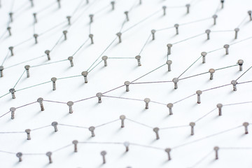 nails in white paper simulation network. linked together by black cotton