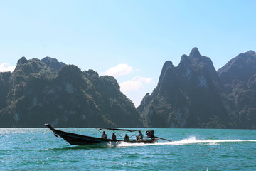 Fototapeta na wymiar touri exploring on a long tail boat with beautiful landscape,mountains ,lake,blue sky and natural attractions from a long tail boat in Ratchaprapha Dam at Khao Sok National Park,Suratthani ,Thailand 