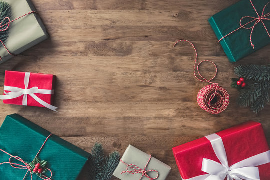 Top view of Christmas gift boxes on a wooden table with pine and mistletoe