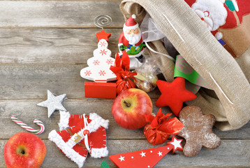 Christmas gifts falling  from  the decorated linen bag, holiday presents on the wooden grey table, holiday concept