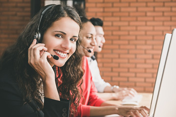 Smiling beautiful woman telemarketing customer service agent working in call center with her team