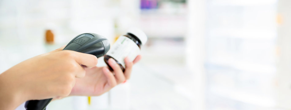 Pharmacist scanning medicine bottle with barcode scanner in pharmacy