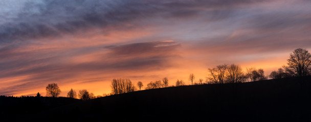 Obraz premium Dramatic Cloudscape panorama of sunrise over forest
