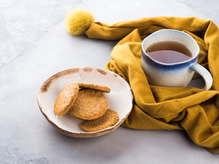 Winter comfort food concept with woman's scarf, mug of tea and cookies. Moment of relax