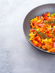Cooking bell peppers with rosemary in frying pan
