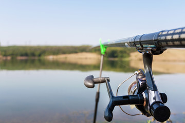 Part of a fishing rod on water and sky background. Selective focus