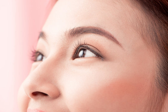 Beautiful asian woman eye with long eyelashes isolated on pink background.