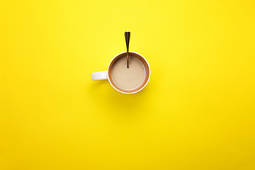 A Cup with coffee and spoon on a colored background. The concept of coffee breaks