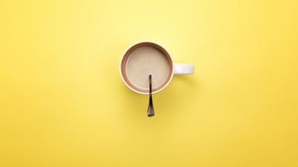 A Cup with coffee and spoon on a colored background. The concept of coffee breaks
