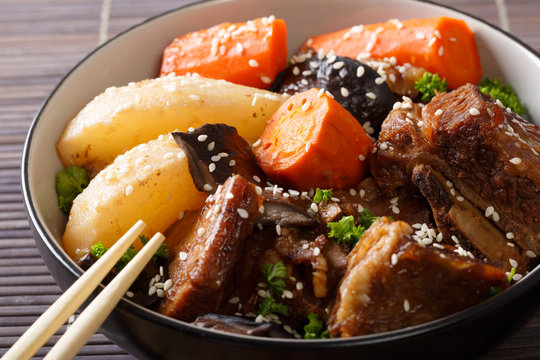Spicy ribs stewed with mushrooms, pears and carrots close-up in a bowl. horizontal