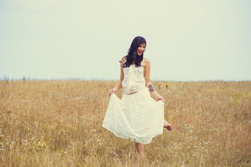 Fototapeta na wymiar Beautiful curly and tanned woman in lace vintage blouse and skirt on a meadow. Concept of retro femininity and tenderness