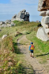 Un petit garçon fait de la randonnée sur le sentier côtier du Gouffre à Plougrescant en Bretagne