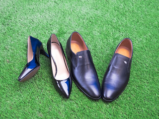 Pair of men's and women's business shoes on green grass background