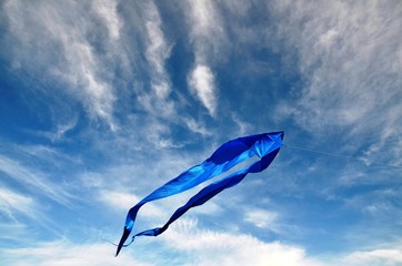 The kite, made of blue silk, hovers high in the dark blue sky against the background of cirrus...