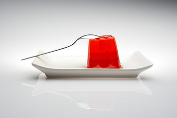 gelatina roja en un plato y cuchara lista para comer - obrazy, fototapety, plakaty