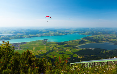 Paraglider flies over the green valley with lakes and towns. Area of the city of Fussen, Germany